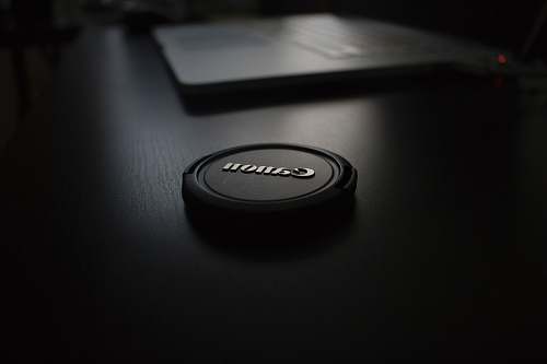 lens cap shallow focus photography of black Canon zoom lens cover cap